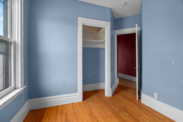 822 35th St, Minneapolis, MN 55408 - unfurnished bedroom with a closet, wood finished floors, multiple windows, and baseboards
