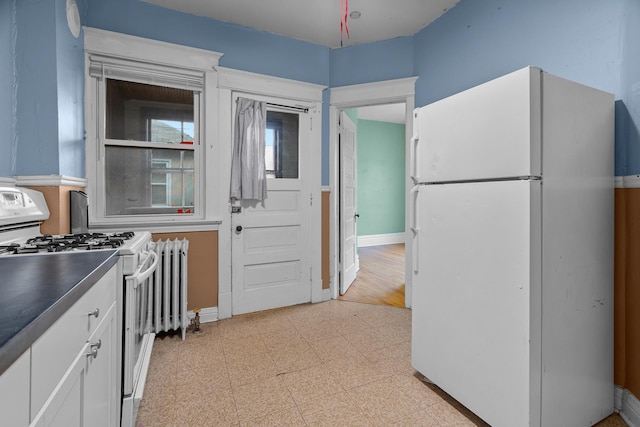 822 35th St, Minneapolis, MN 55408 - kitchen with white appliances, radiator heating unit, white cabinets, baseboards, and dark countertops
