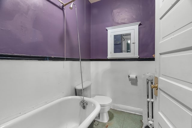 822 35th St, Minneapolis, MN 55408 - bathroom featuring a freestanding tub, toilet, tile patterned flooring, baseboards, and radiator heating unit
