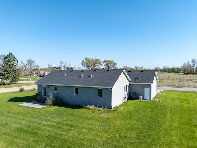 back of house with a yard, roof with shingles, and central AC unit