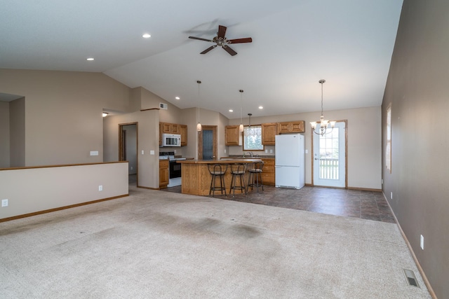 kitchen with white appliances, open floor plan, a kitchen island, vaulted ceiling, and baseboards