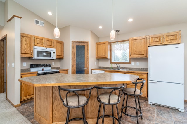 kitchen featuring white appliances, a sink, vaulted ceiling, a kitchen island, and a kitchen breakfast bar