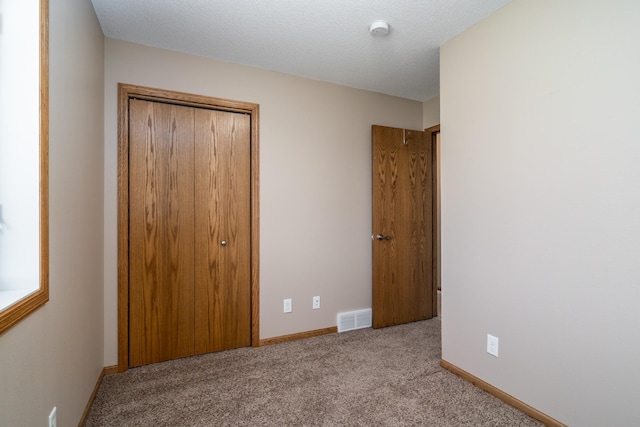 unfurnished bedroom with a closet, carpet, and baseboards