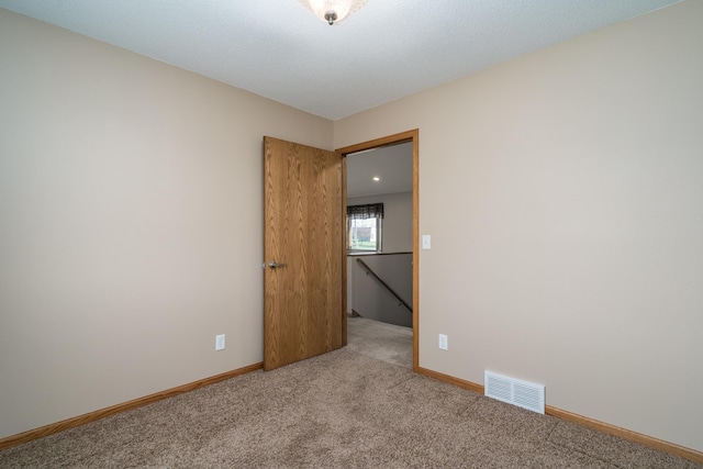 unfurnished room featuring light colored carpet and baseboards