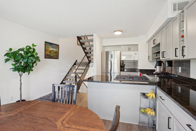 5624 Brookdale Dr N, Brooklyn Park, MN 55443 - kitchen featuring appliances with stainless steel finishes, a sink, dark wood-style floors, a peninsula, and dark stone counters