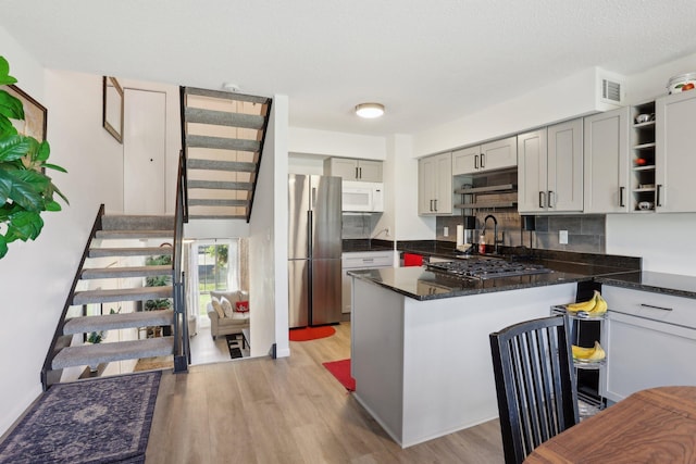 5624 Brookdale Dr N, Brooklyn Park, MN 55443 - kitchen featuring appliances with stainless steel finishes, light wood-style floors, a peninsula, and decorative backsplash