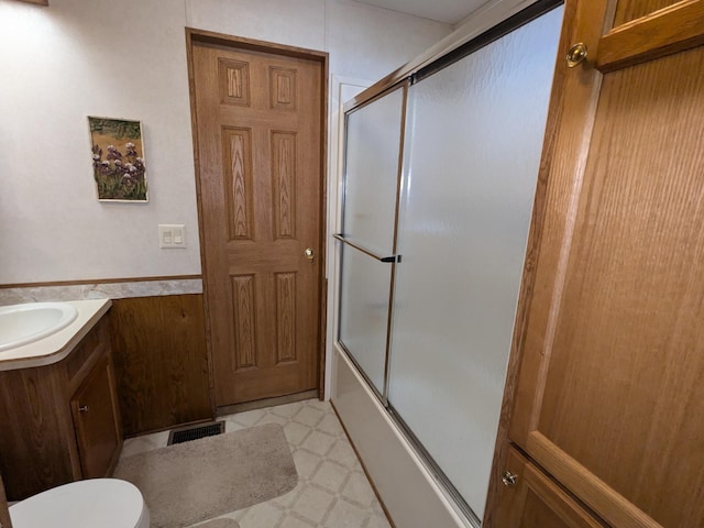 2221 Reubens Ln SW Unit 46, Farwell, MN 56327 - full bathroom with vanity, combined bath / shower with glass door, toilet, tile patterned floors, and a wainscoted wall