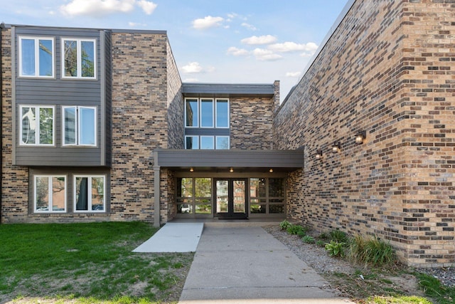 450 Ford Rd Unit 231, Saint Louis Park, MN 55426 - view of exterior entry featuring a yard and brick siding