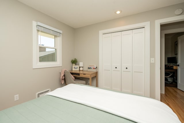 bedroom with wood finished floors, a closet, and recessed lighting