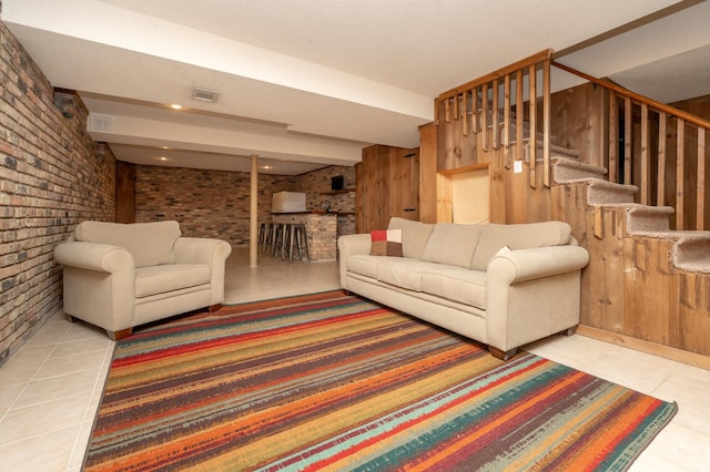 tiled living area featuring brick wall and stairway