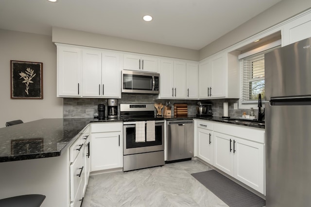 kitchen with appliances with stainless steel finishes, a peninsula, backsplash, white cabinetry, and recessed lighting