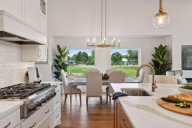 kitchen featuring stainless steel gas stovetop, custom range hood, a sink, a chandelier, and dark wood-type flooring