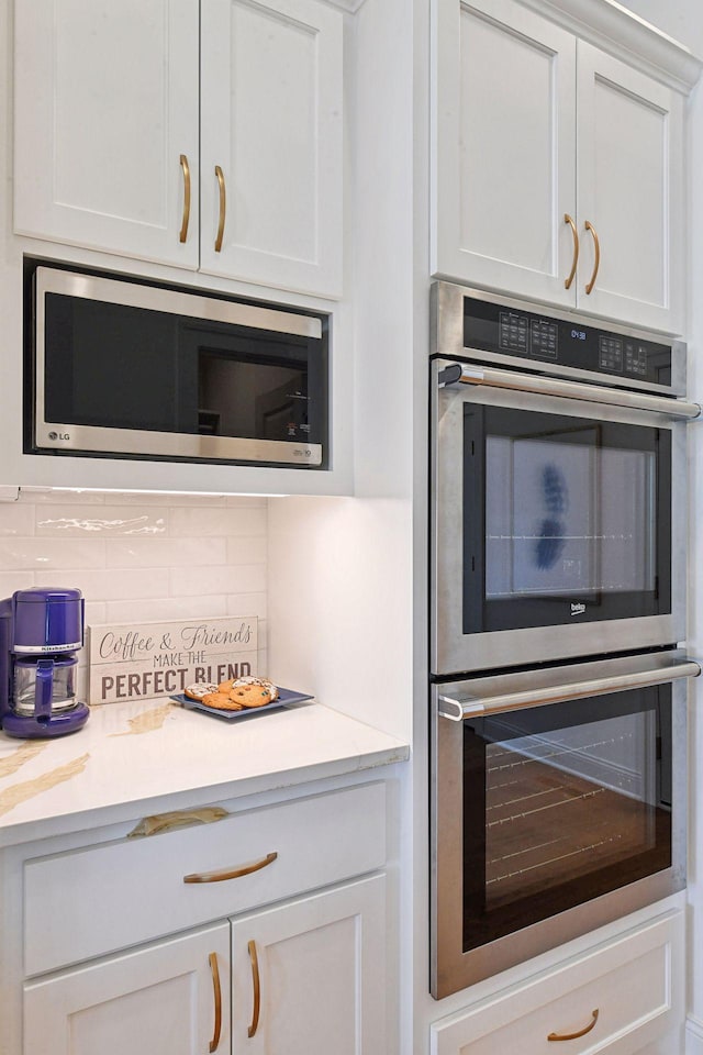 kitchen featuring stainless steel appliances, tasteful backsplash, white cabinets, and light countertops