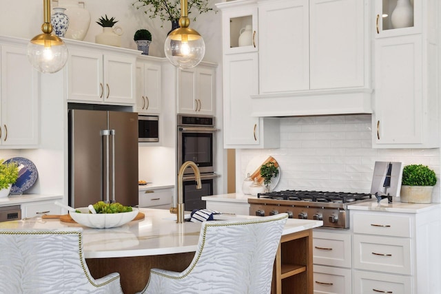 kitchen with appliances with stainless steel finishes, white cabinetry, hanging light fixtures, and glass insert cabinets