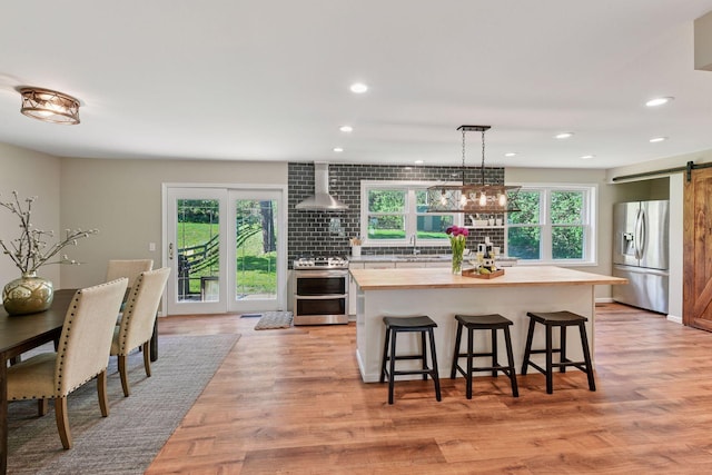 550 Wheeler Dr, Excelsior, MN 55331 - kitchen with stainless steel appliances, butcher block counters, a barn door, a sink, and wall chimney exhaust hood