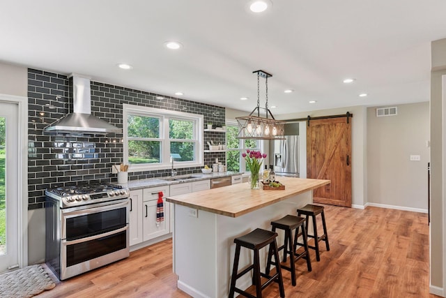 550 Wheeler Dr, Excelsior, MN 55331 - kitchen featuring stainless steel appliances, wall chimney exhaust hood, butcher block countertops, a sink, and a barn door