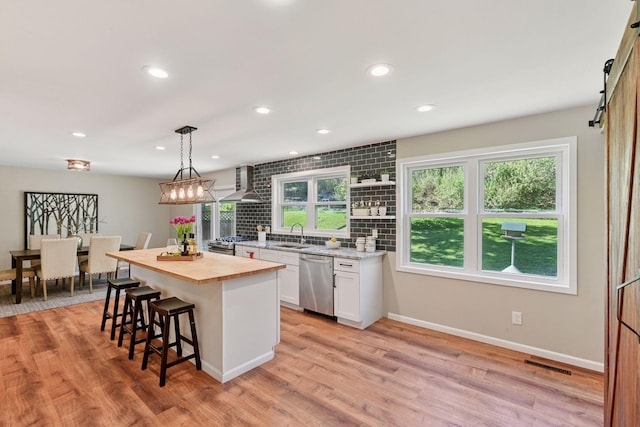 550 Wheeler Dr, Excelsior, MN 55331 - kitchen with appliances with stainless steel finishes, wooden counters, wall chimney exhaust hood, a kitchen bar, and white cabinets