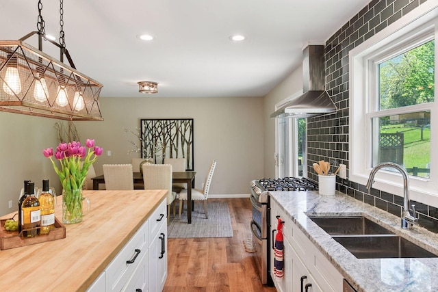 550 Wheeler Dr, Excelsior, MN 55331 - kitchen with wooden counters, a sink, wall chimney range hood, range with two ovens, and light wood-type flooring