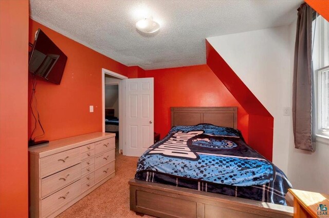 bedroom featuring light colored carpet and a textured ceiling