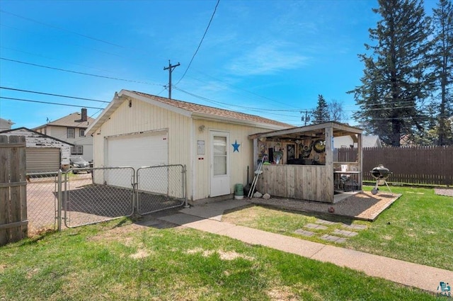 view of side of home featuring a detached garage, an outbuilding, and a gate
