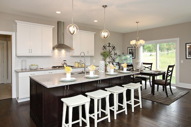 19587 Hammock Ave, Lakeville, MN 55044 - kitchen with wall chimney exhaust hood, tasteful backsplash, white cabinetry, an island with sink, and a chandelier
