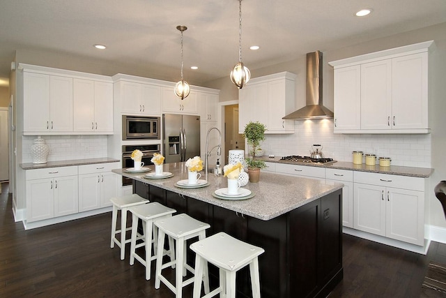 19587 Hammock Ave, Lakeville, MN 55044 - kitchen featuring stainless steel appliances, wall chimney exhaust hood, dark wood-type flooring, tasteful backsplash, and a kitchen breakfast bar