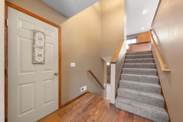 staircase featuring wood finished floors, baseboards, and recessed lighting