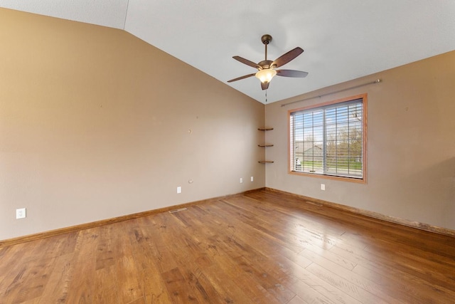 spare room featuring vaulted ceiling, a ceiling fan, wood finished floors, and baseboards