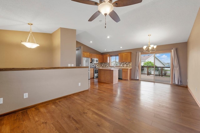 unfurnished living room featuring vaulted ceiling, a chandelier, light wood finished floors, baseboards, and a ceiling fan
