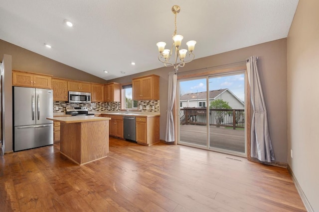 kitchen with stainless steel appliances, lofted ceiling, decorative backsplash, light countertops, and a chandelier