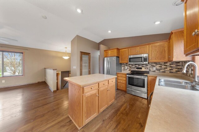 kitchen with stainless steel appliances, a sink, lofted ceiling, light countertops, and a center island