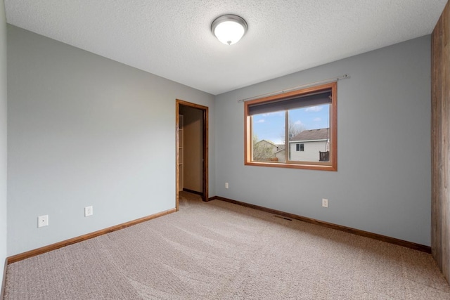 carpeted empty room featuring baseboards and a textured ceiling