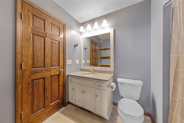 bathroom featuring tile patterned floors, toilet, vanity, baseboards, and a textured ceiling