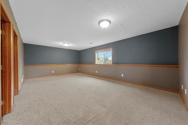 spare room with carpet flooring, a textured ceiling, and baseboards