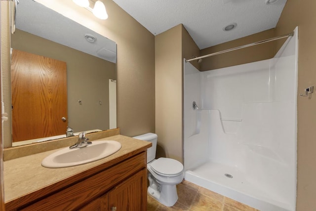 bathroom featuring toilet, a shower, a textured ceiling, vanity, and tile patterned floors