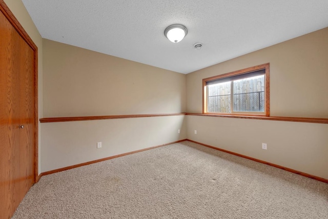 carpeted spare room featuring baseboards and a textured ceiling