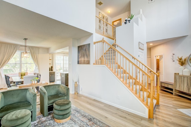 living area featuring stairs, wood finished floors, baseboards, and a high ceiling