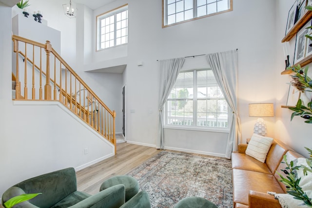 living room featuring a high ceiling, healthy amount of natural light, wood finished floors, and a chandelier