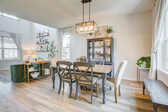 dining room featuring light wood-style flooring, baseboards, and a chandelier