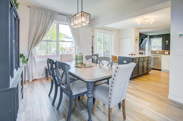 dining room featuring light wood-style flooring, plenty of natural light, a chandelier, and baseboards