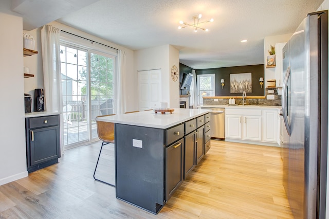 kitchen with stainless steel appliances, light wood-style flooring, healthy amount of natural light, a kitchen island, and recessed lighting