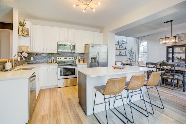 kitchen featuring stainless steel appliances, a sink, a chandelier, and open shelves