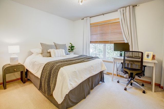 carpeted bedroom with baseboards and a desk