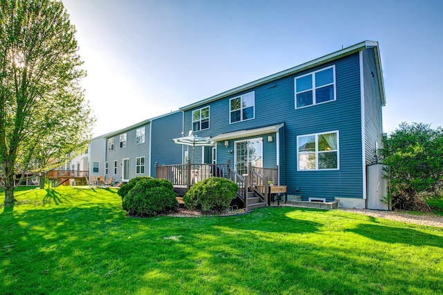 rear view of house featuring a wooden deck and a yard