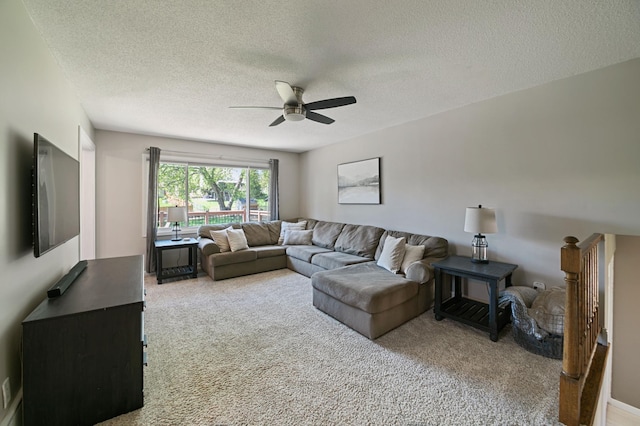 carpeted living room featuring a ceiling fan and a textured ceiling