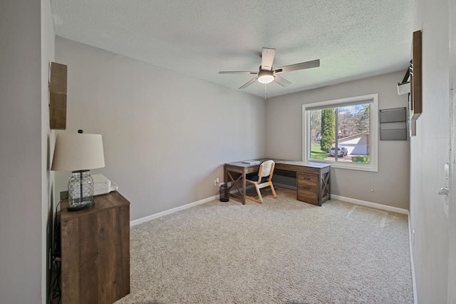 office featuring a textured ceiling, a ceiling fan, light carpet, and baseboards