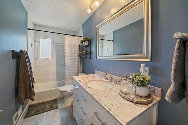 bathroom featuring vanity, wood finished floors, toilet, shower / bath combo, and a textured ceiling