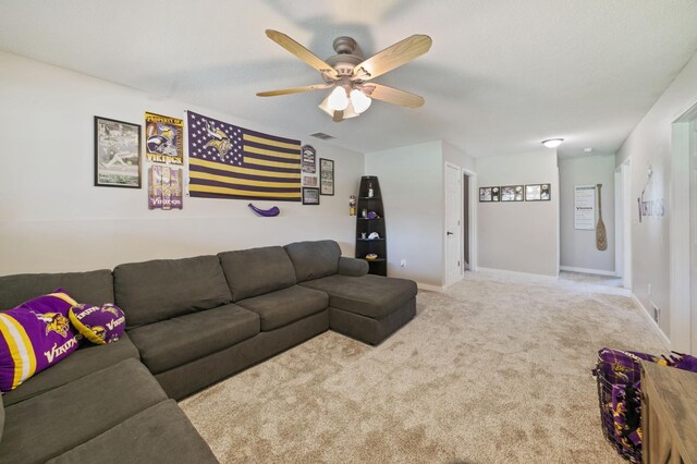 carpeted living area with a ceiling fan and baseboards