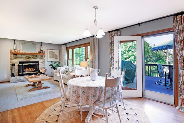 dining room featuring wood finished floors, a chandelier, and a brick fireplace