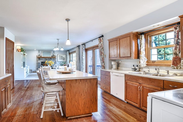 kitchen with white appliances, a sink, open floor plan, and wood finished floors